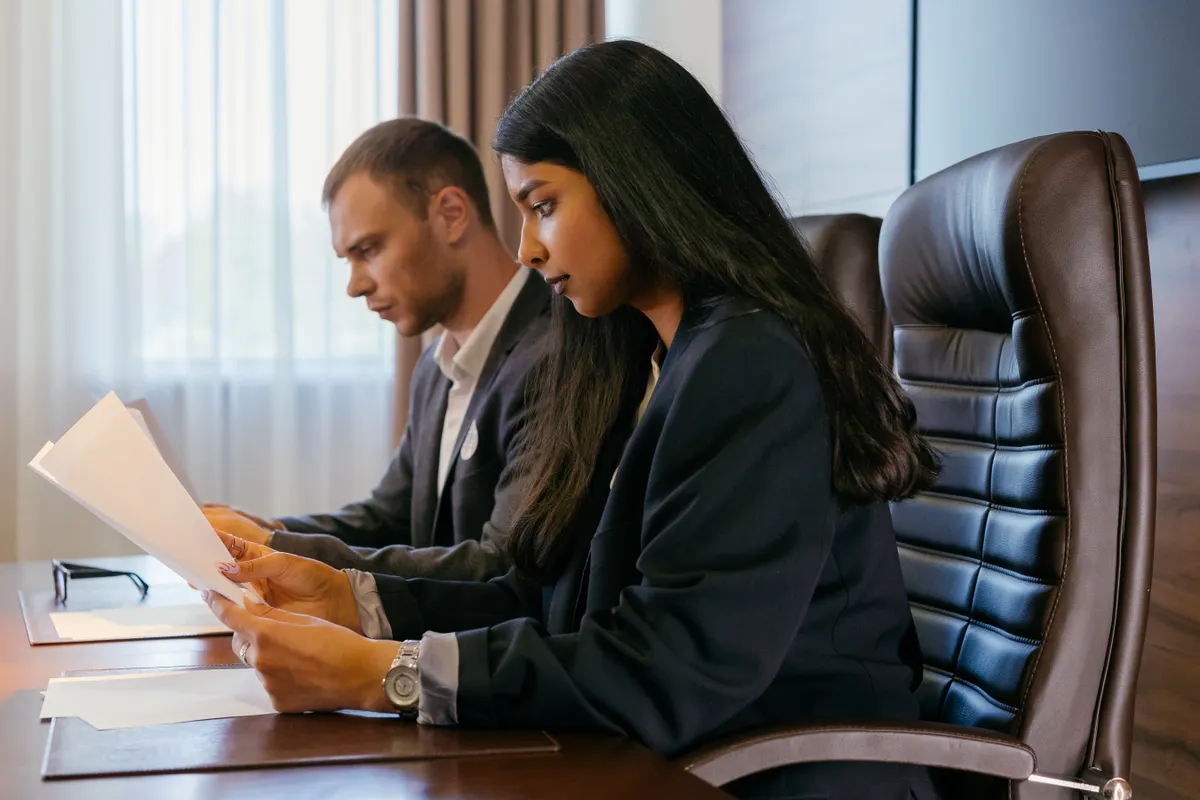 Two colleagues reviewing documents together at a conference table.