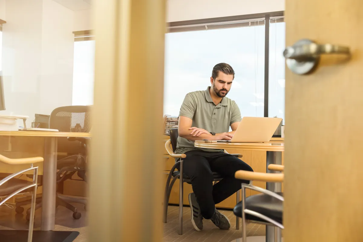 A professional working on a laptop in a bright office.